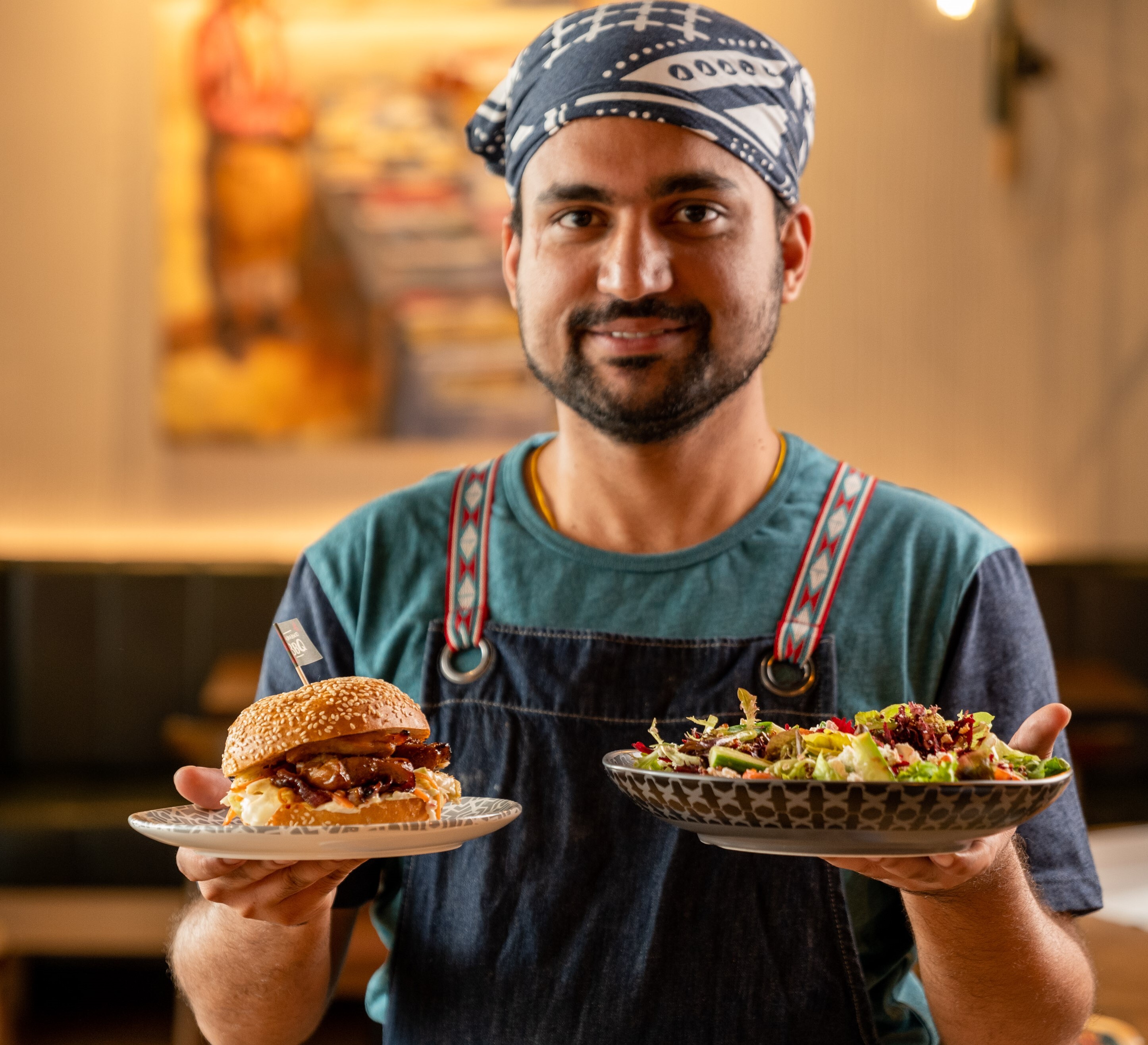 A Nando's staff member carrying a burger and a salad
