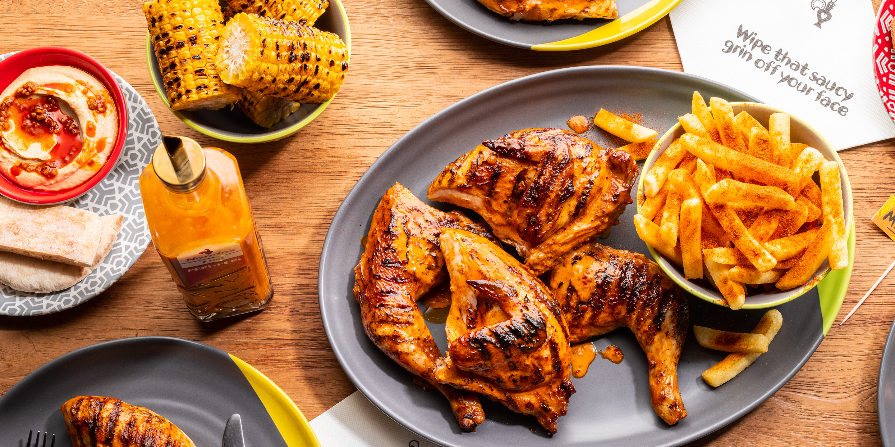 a Nando’s meal on a table including PERi-PERi chicken, a salad, chips, and a selection of sides